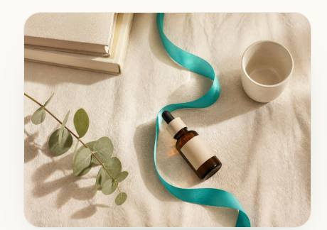 Amber serum bottle on cream linen with a Tiffany-blue silk ribbon and eucalyptus
